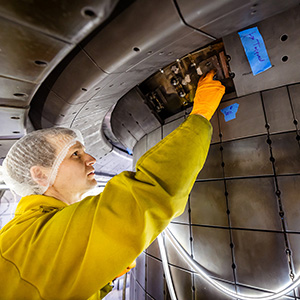 An engineer in a yellow jumpsuit works on tiles