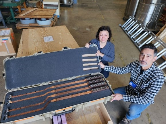 Two scientists standing with a box containing copper waveguides.