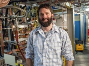 A scientist stands in front of equipment.