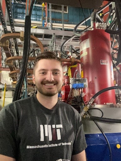 A scientist stands in front of a klystron.