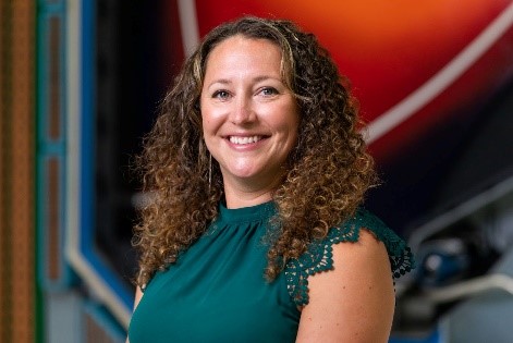 A scientist smiles in front of the DIII-D cross-section.