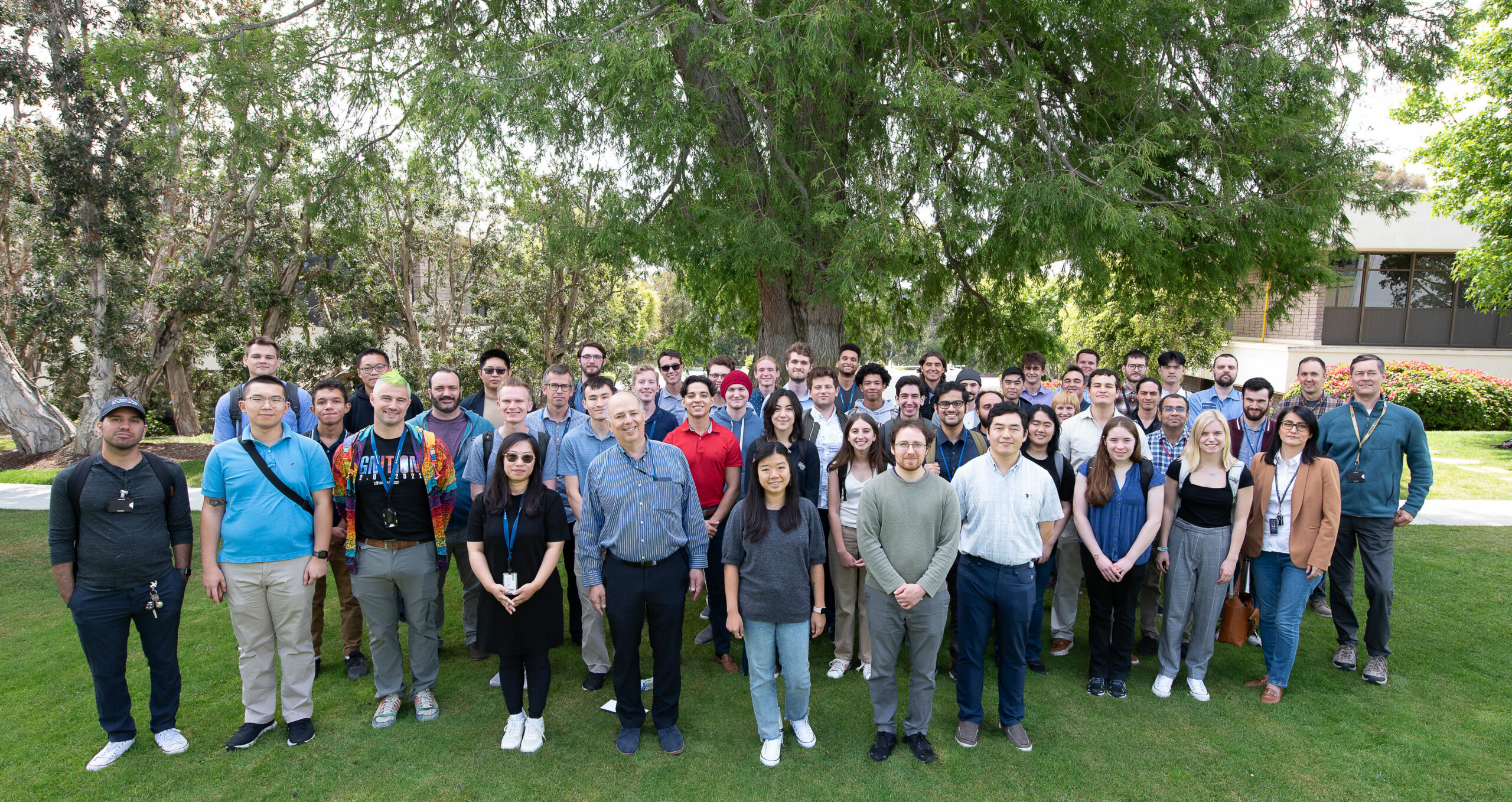 Mentors and student interns stand in front of a tree.